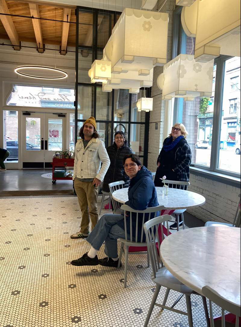 AMM staff smile at the camera while getting coffee