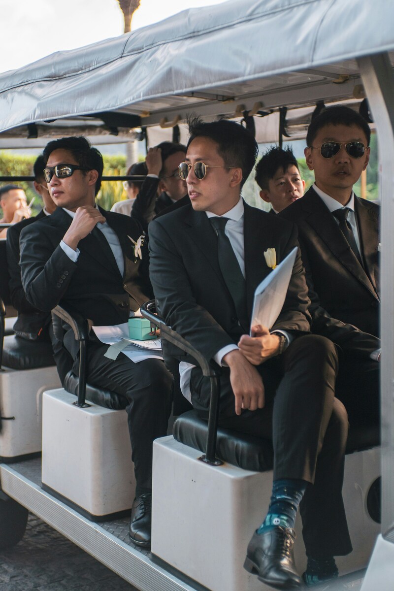 Groomsmen being driven to wedding venue in small open van