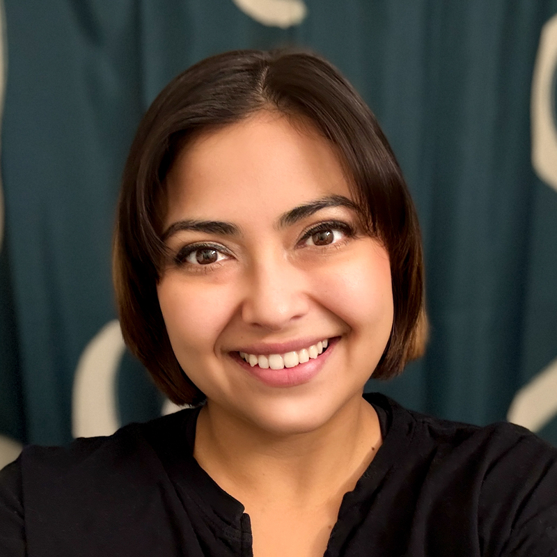 Headshot of Marisa Correa, AMM's events and marketing coordinator. Marisa has brightly dyed red hair and is smiling toward the camera