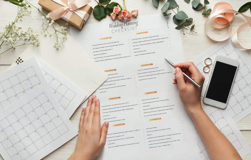 Close up of wedding planning checklist and calendar, woman holds a pen