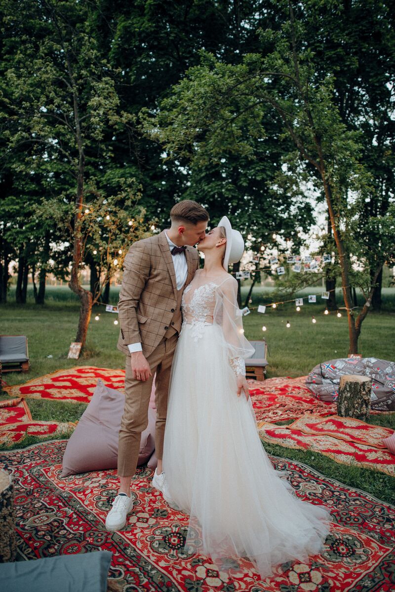 young bride and groom kiss outdoors, bohemian wedding in park