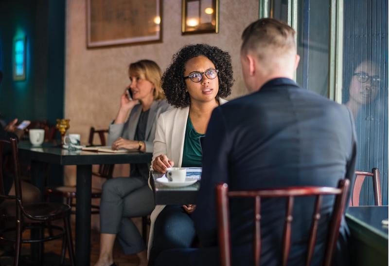 image is a photograph of a young couple talking about wedding planning in a restaurant