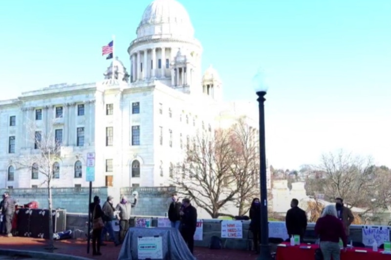 wedding vendors gather outside the capital building in Rhode Island to raise awareness about a lack of industry guidance and assistance during covid, people on sidewalks holding signs with capital building in background 