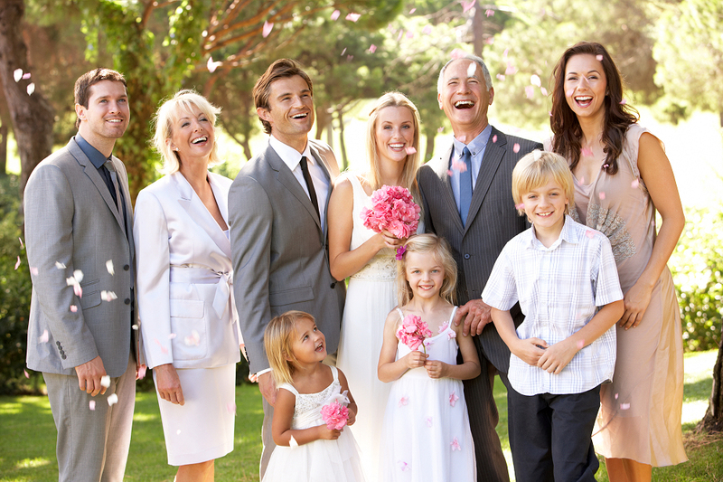 a large outdoor family wedding with a bride and a groom posing with older members and children for the wedding photographer at a covenant marriage ceremony