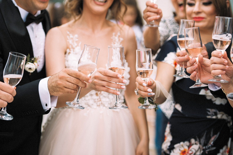 couple celebrates their wedding with a toast of champagne outside with their friends during a group wedding ceremony 