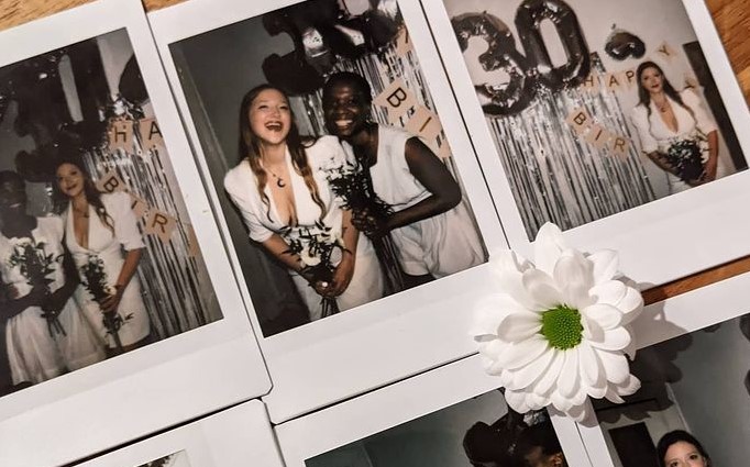 Polaroids of two friends on their wedding day, laid out on a table with a daisy
