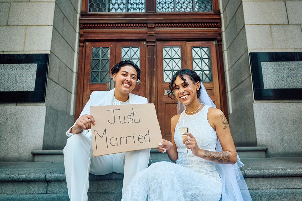 Newlyweds pose outside a courthouse after eloping with a sign that reads 'just married'