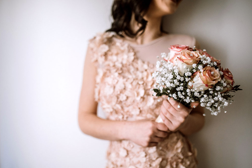 Close up of a bride in a pink wedding dress holding a bouquet of flowers