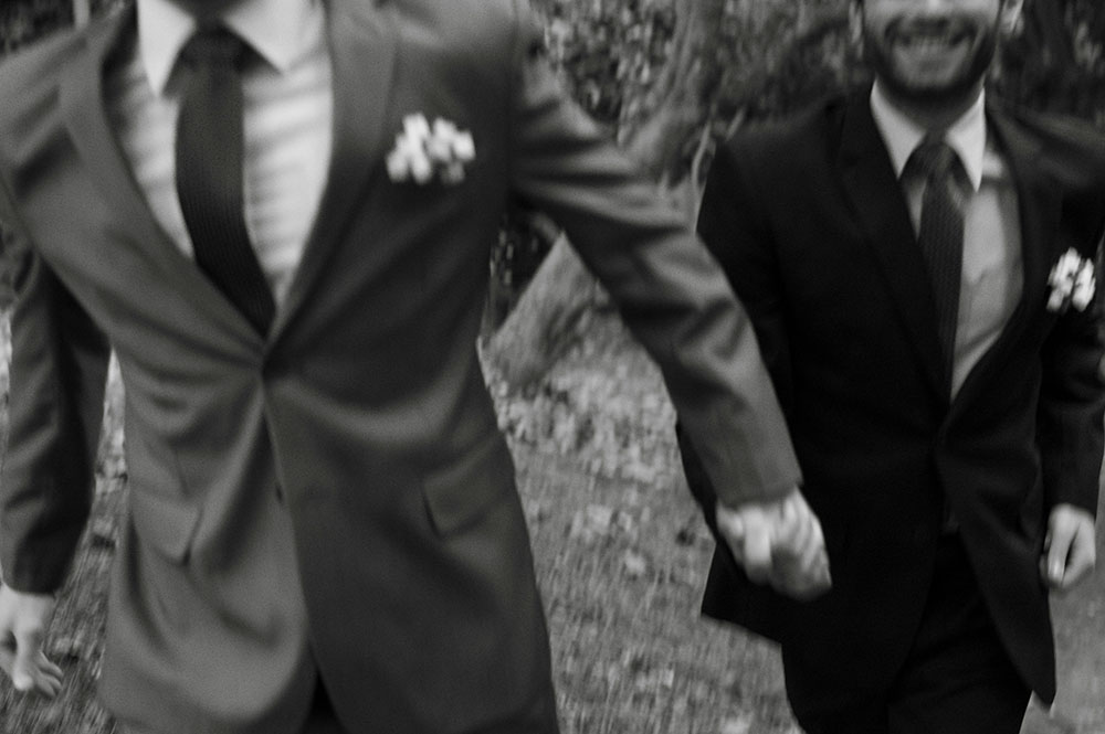 Two grooms hold hands and smile on the wedding day