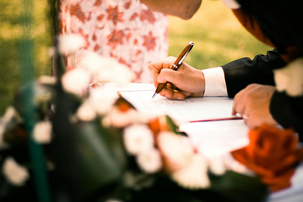 Close up of a newlywed signing the marriage license