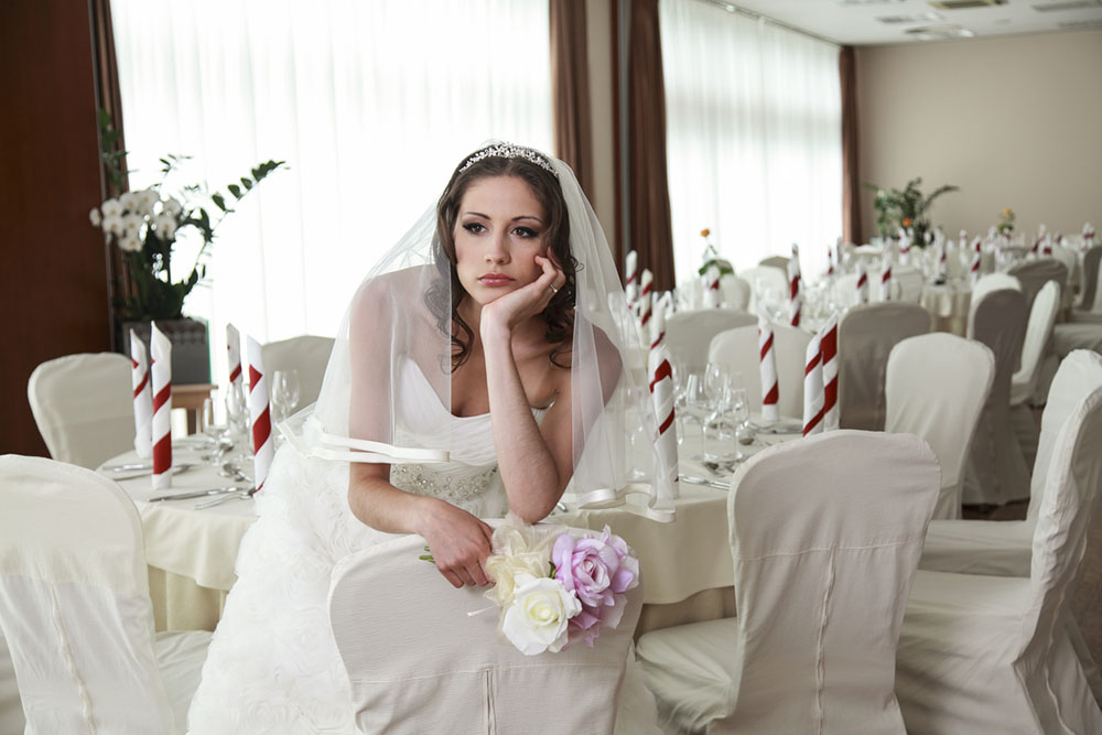 A bride sits at a table alone, lonely