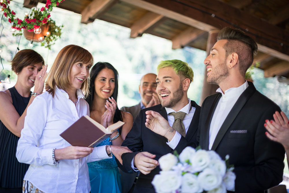 happy wedding scene, officiant performs LGBTQ wedding outdoors with guests