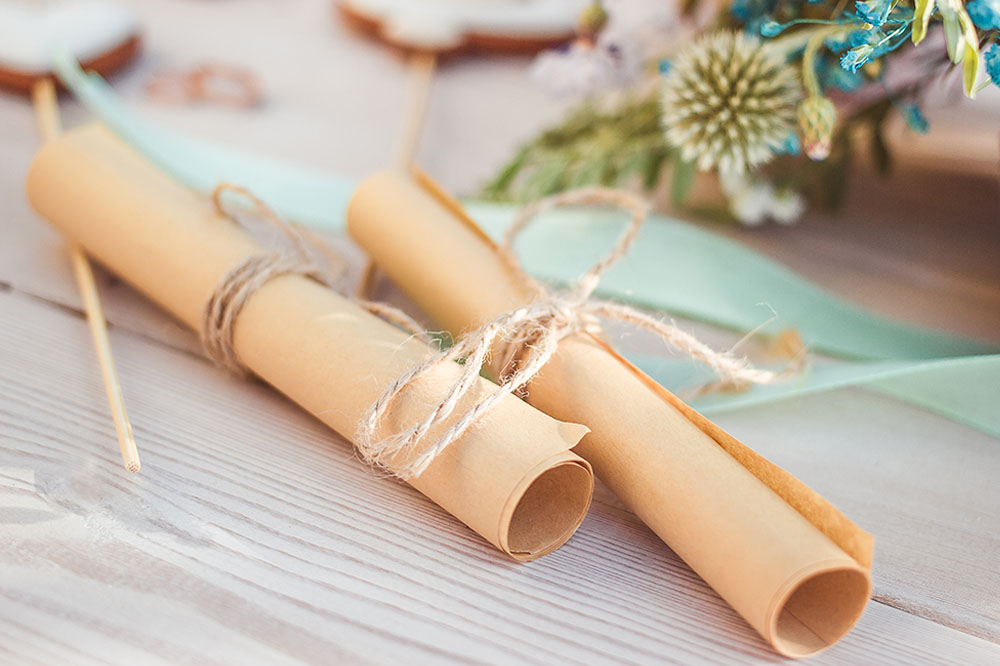 Votos matrimoniales escritos a mano, enrollados en pergaminos y decorados
