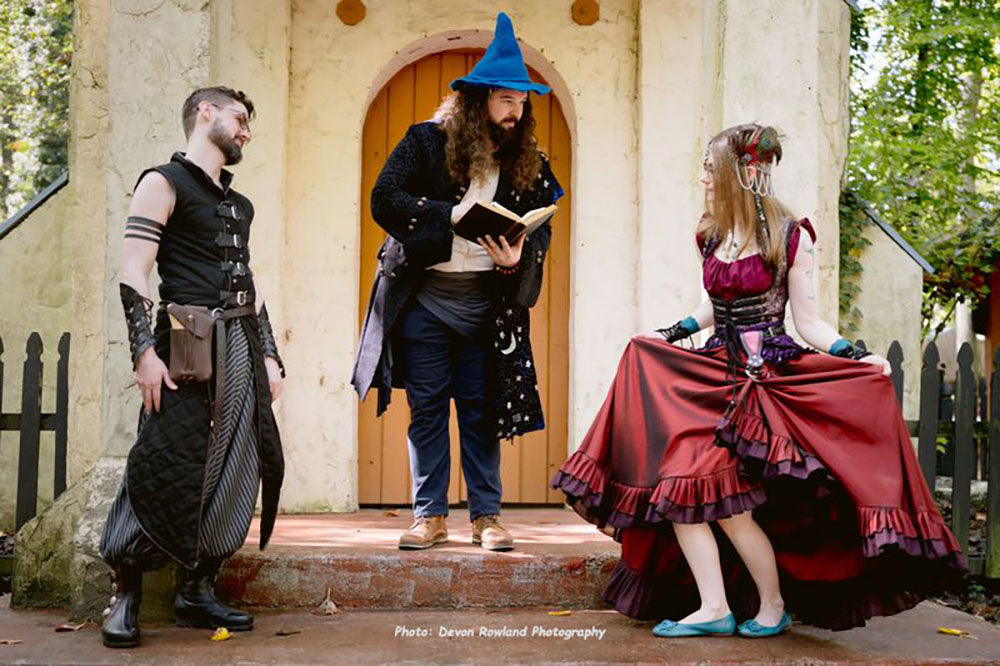 bride and groom pose with wedding officaint at ren faire wedding 