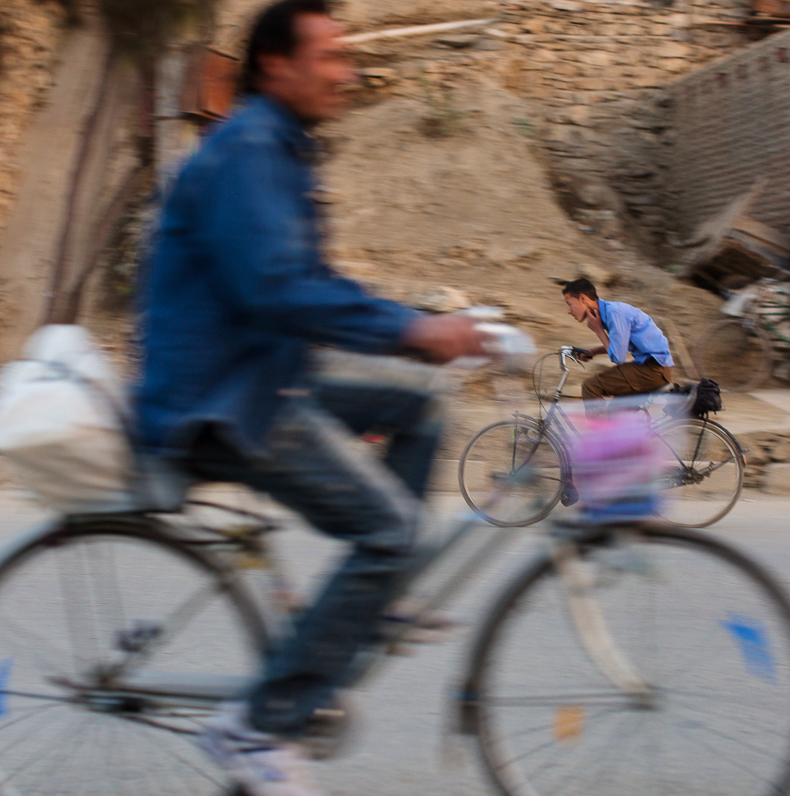 Men riding bikes in front of a hill of dirt