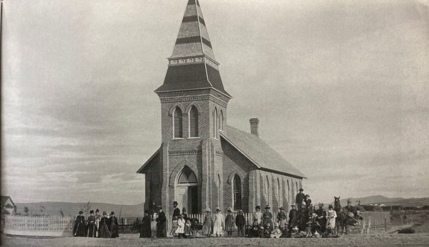 The old First Baptist Church with people walking around in Blackfoot, Idaho, circa 1887.