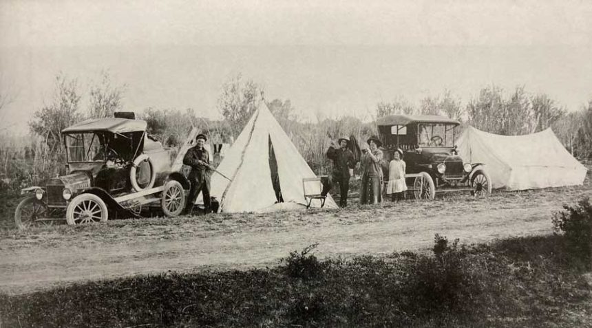 Tents, people, and automobiles pictured near a path on a Salmon River trip.