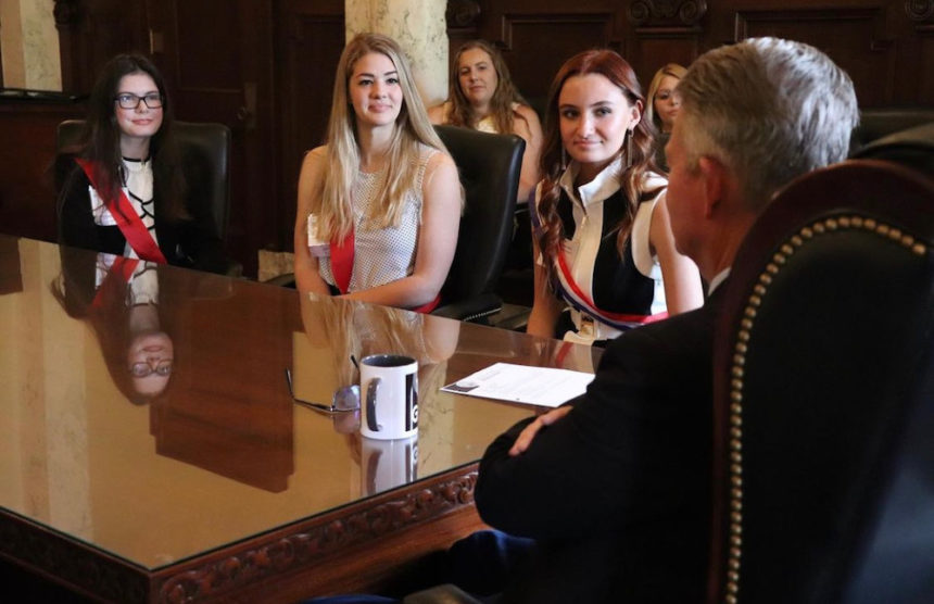 2022 Photo of Girls State Governor Tessa Dalton seated next to Governor Brad Little with other Girls State delegates