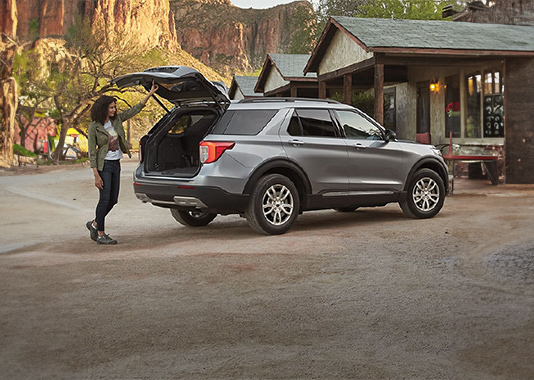 Silver vehicle with person opening the liftgate