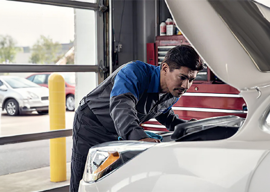 White vehicle with person inspecting under the hood