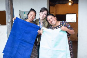 the-root-collective-founder-bethany-tran-posing-with-two-weavers-she-partners-with-through-a-local-weaving-cooperative-women-holding-fabric