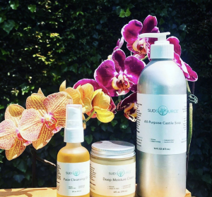 sudsource-products-in-glass-and-aluminum-bottles-displayed-with-orchids