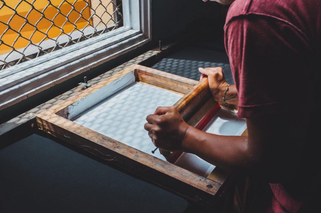 Man Uses Screen Printer by Window