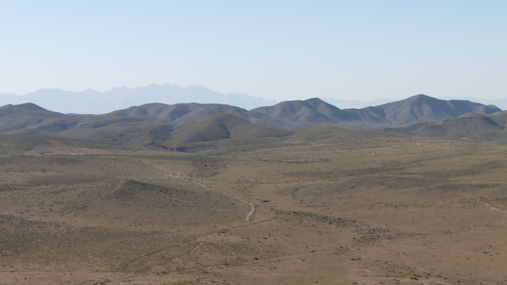 HD stock footage aerial video of an arid plain and mountain ranges near