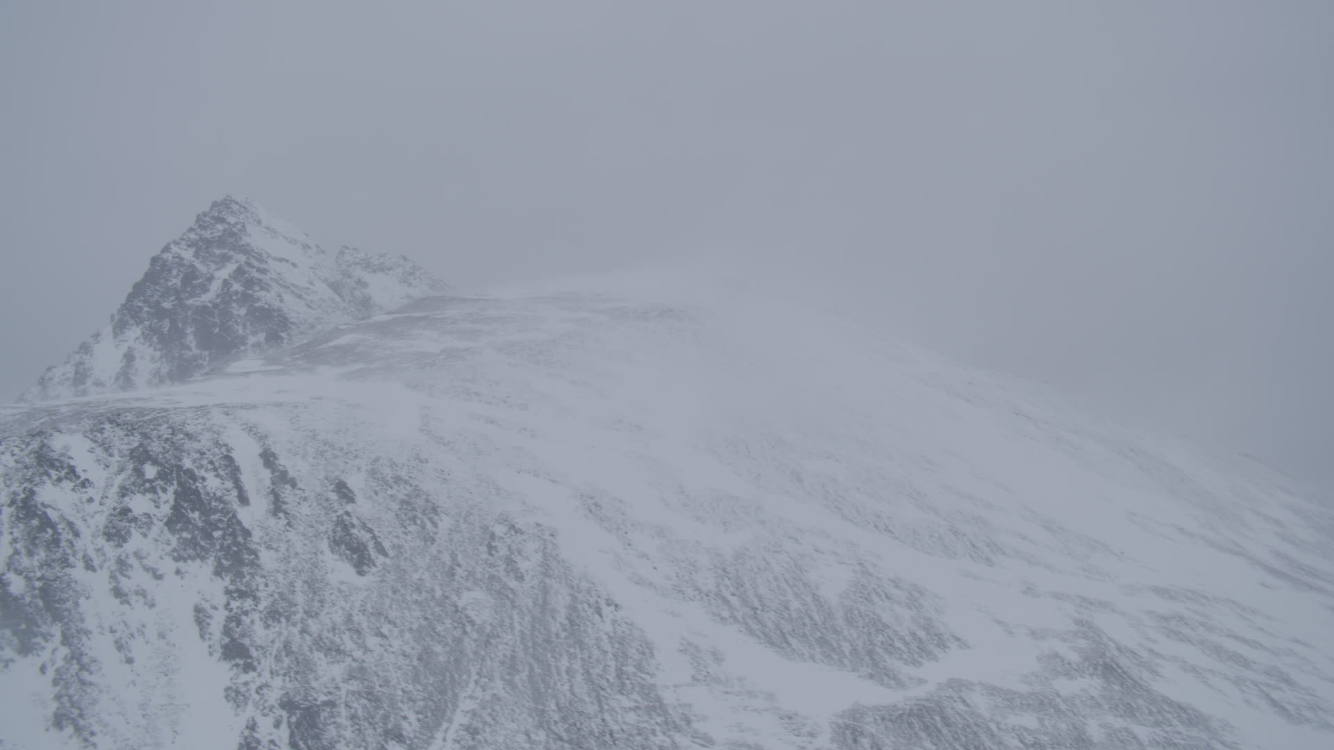 4K stock footage aerial video wind blowing snow off mountain ridge