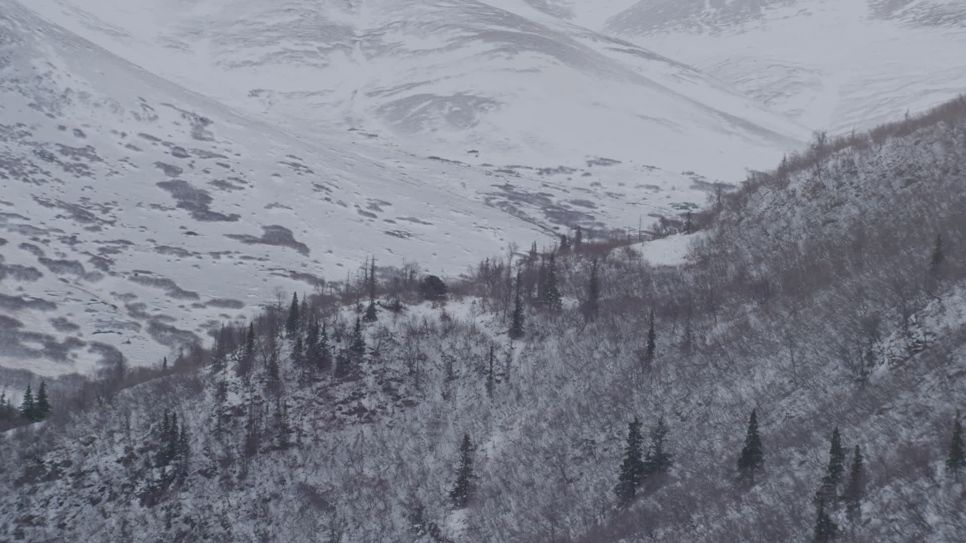 4K stock footage aerial video rounding a snow covered slope revealing