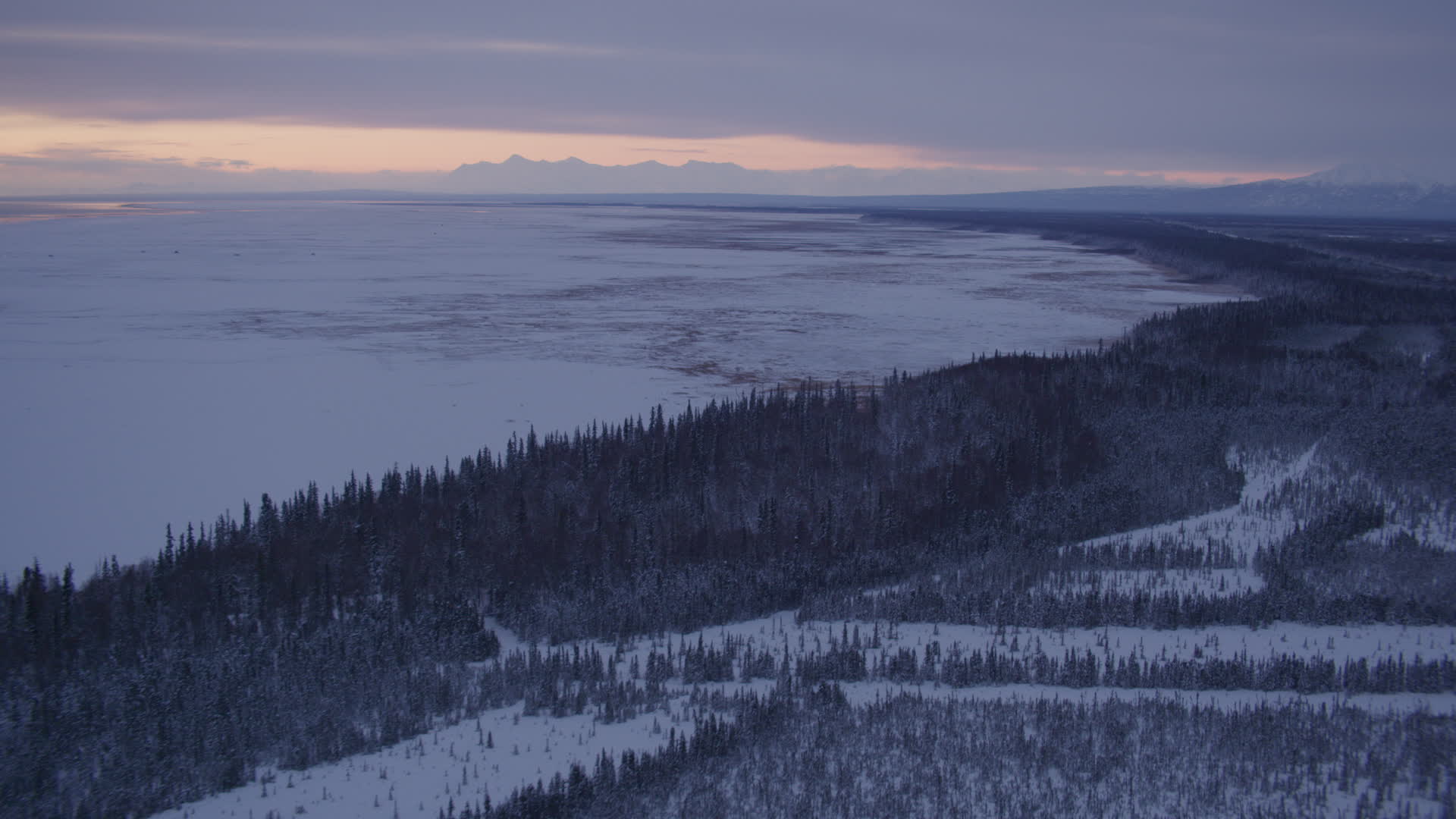 4K stock footage aerial video following snowy, wooded shore of Point