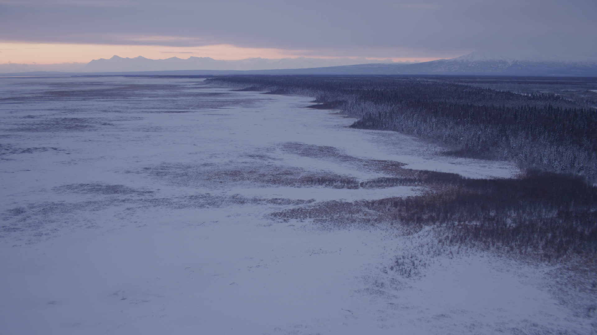 4K stock footage aerial video flying over frozen, snow covered ground at twilight, Point