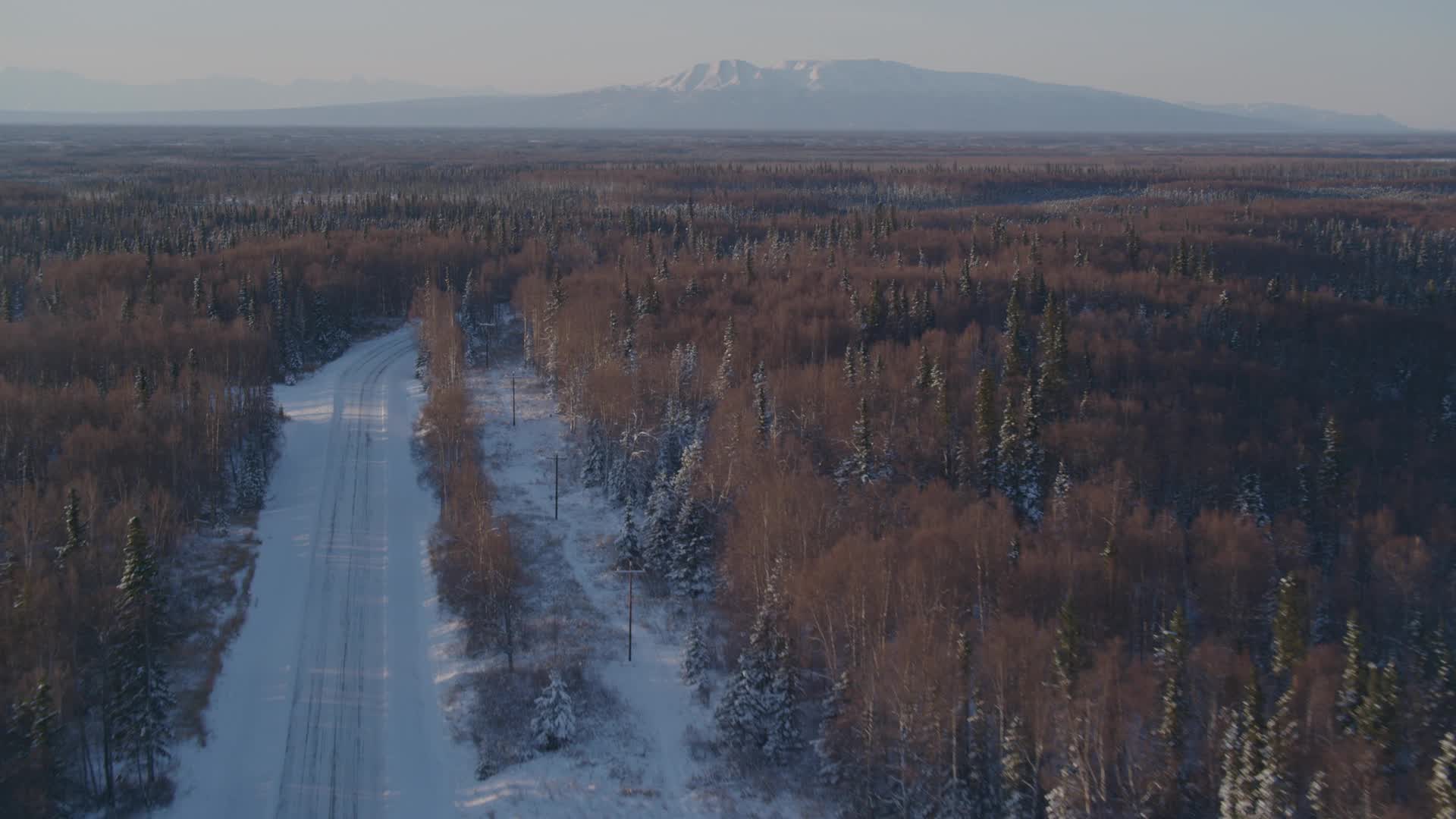 4K stock footage aerial video following a deserted snowy rural highway