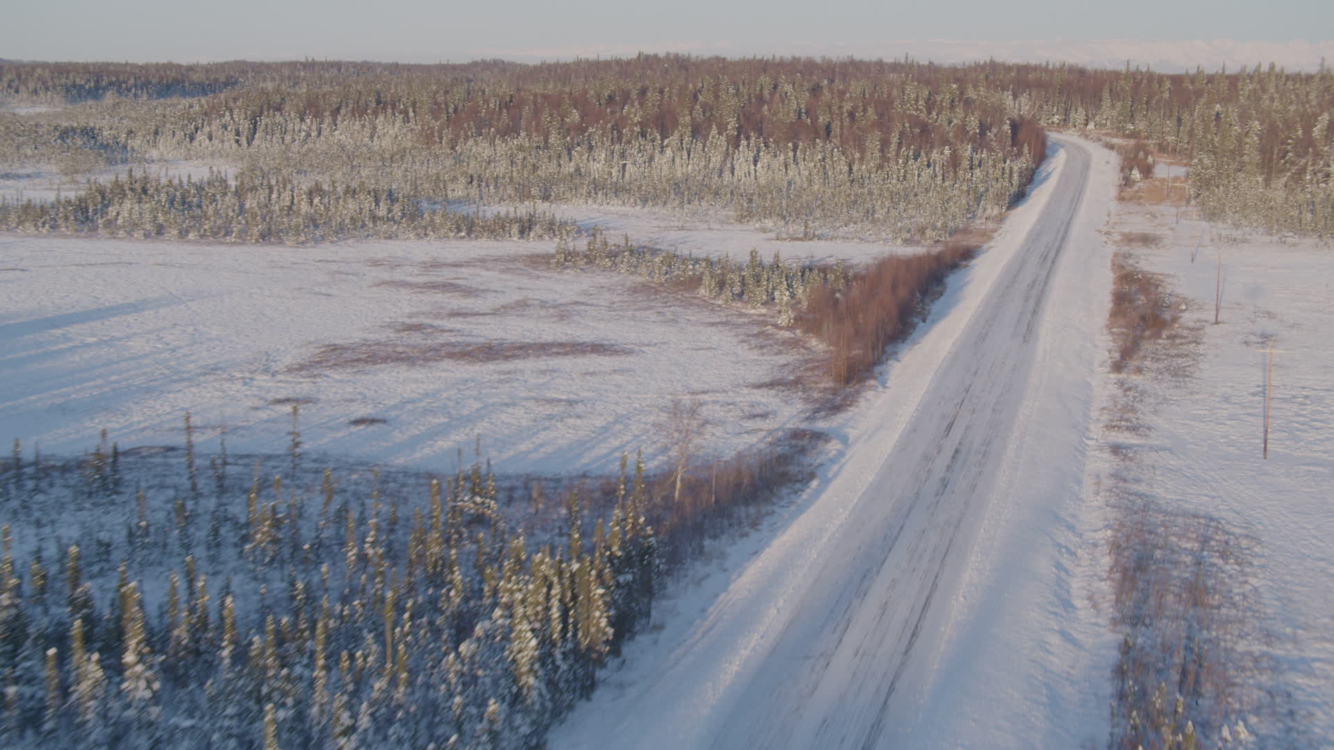 4K stock footage aerial video following a deserted snowy rural highway in Point MacKenzie
