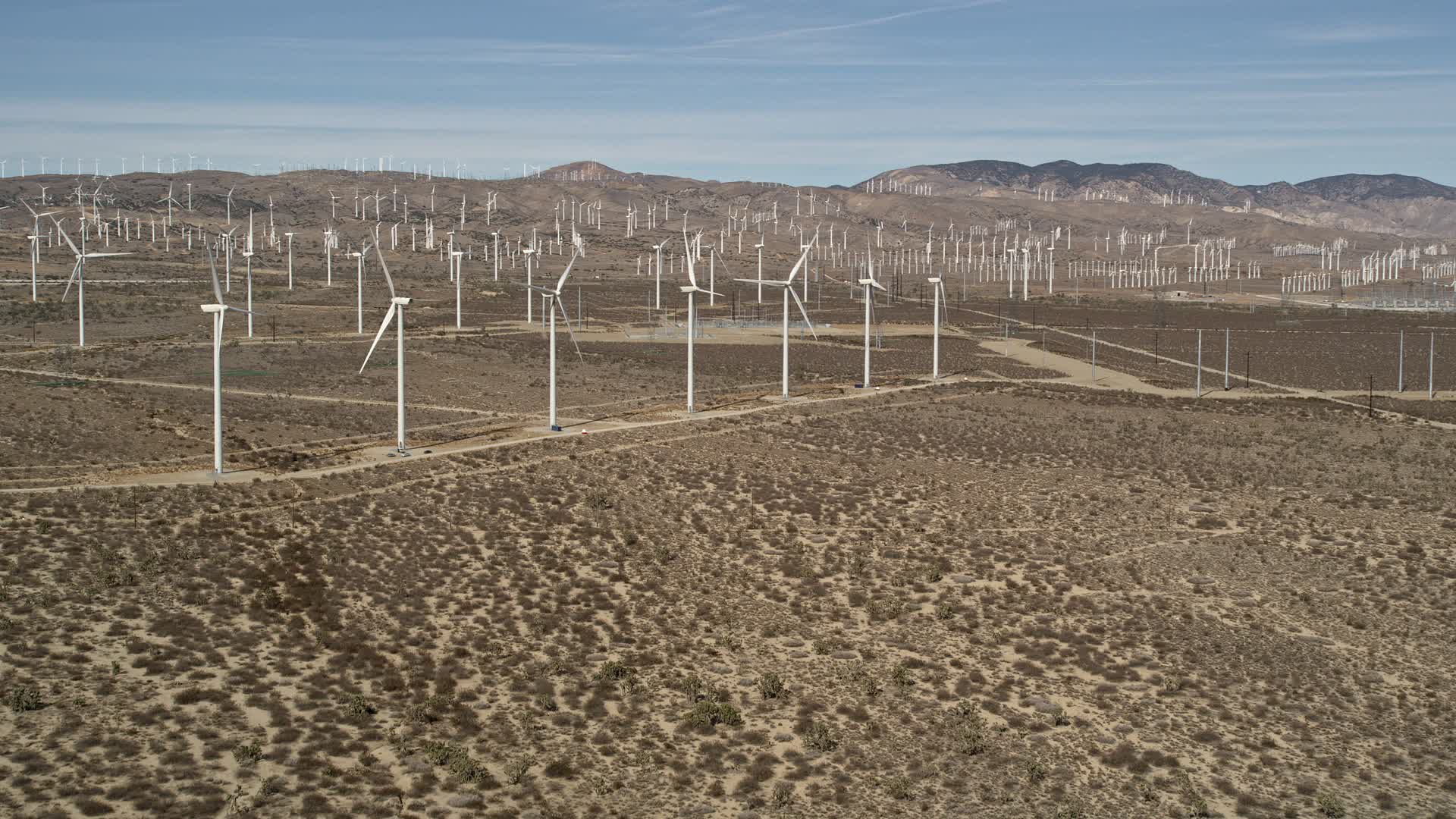 5K stock footage aerial video approach a row of windmills at a wind farm in the Mojave Desert