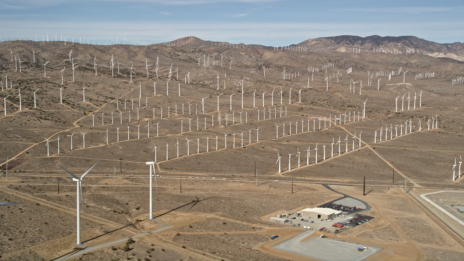 5K stock footage aerial video of rows of windmills at a wind energy farm in the Mojave Desert of