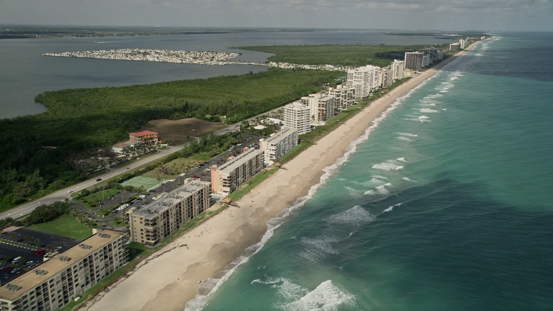 5K stock footage aerial video of beachside apartment buildings and blue