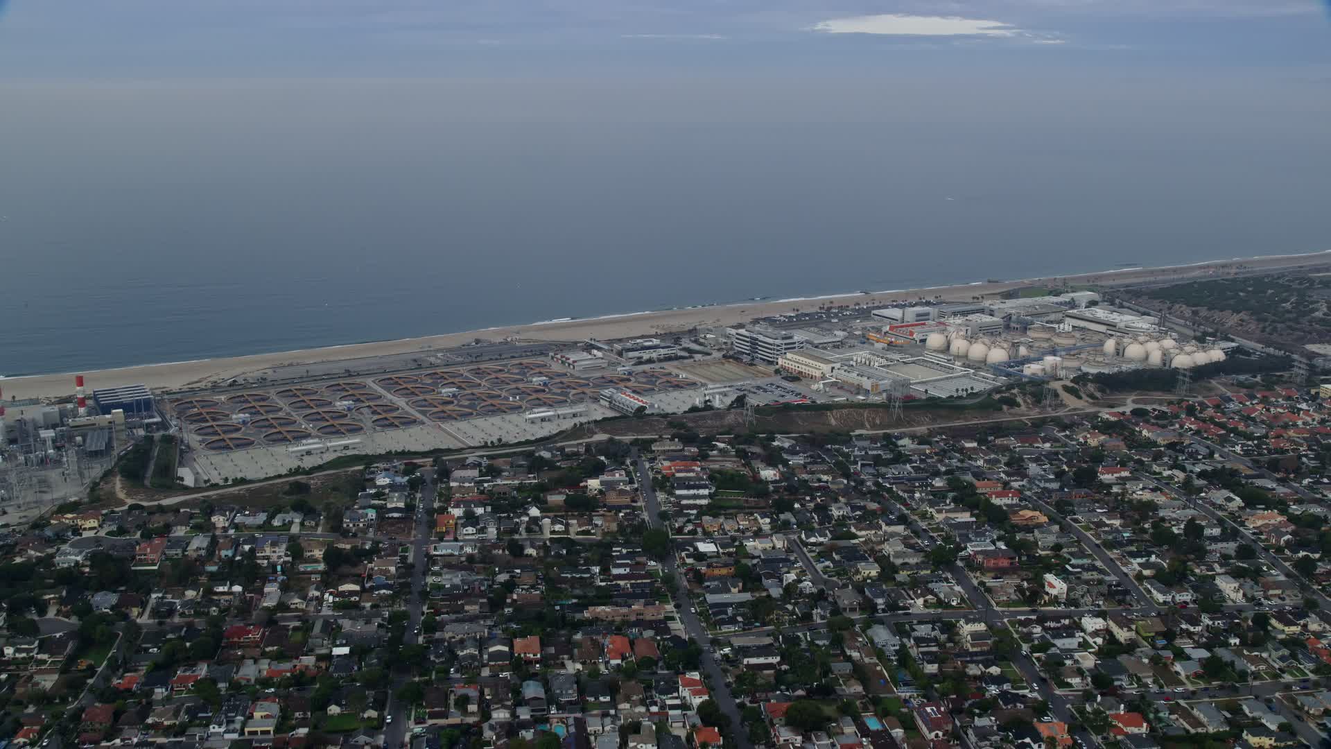 7.6K stock footage aerial video flying over coastal community towards Dockweiler beach and water