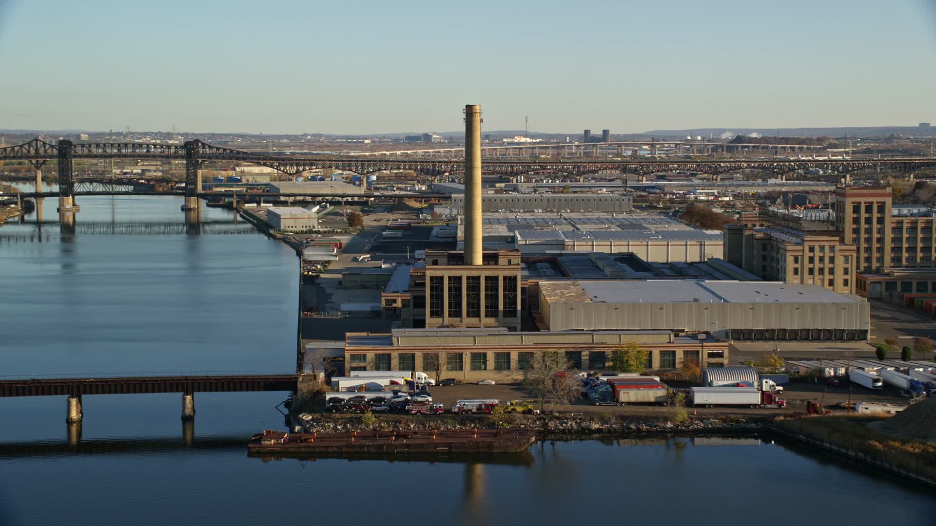 5.5K stock footage aerial video of riverfront factory at sunrise in