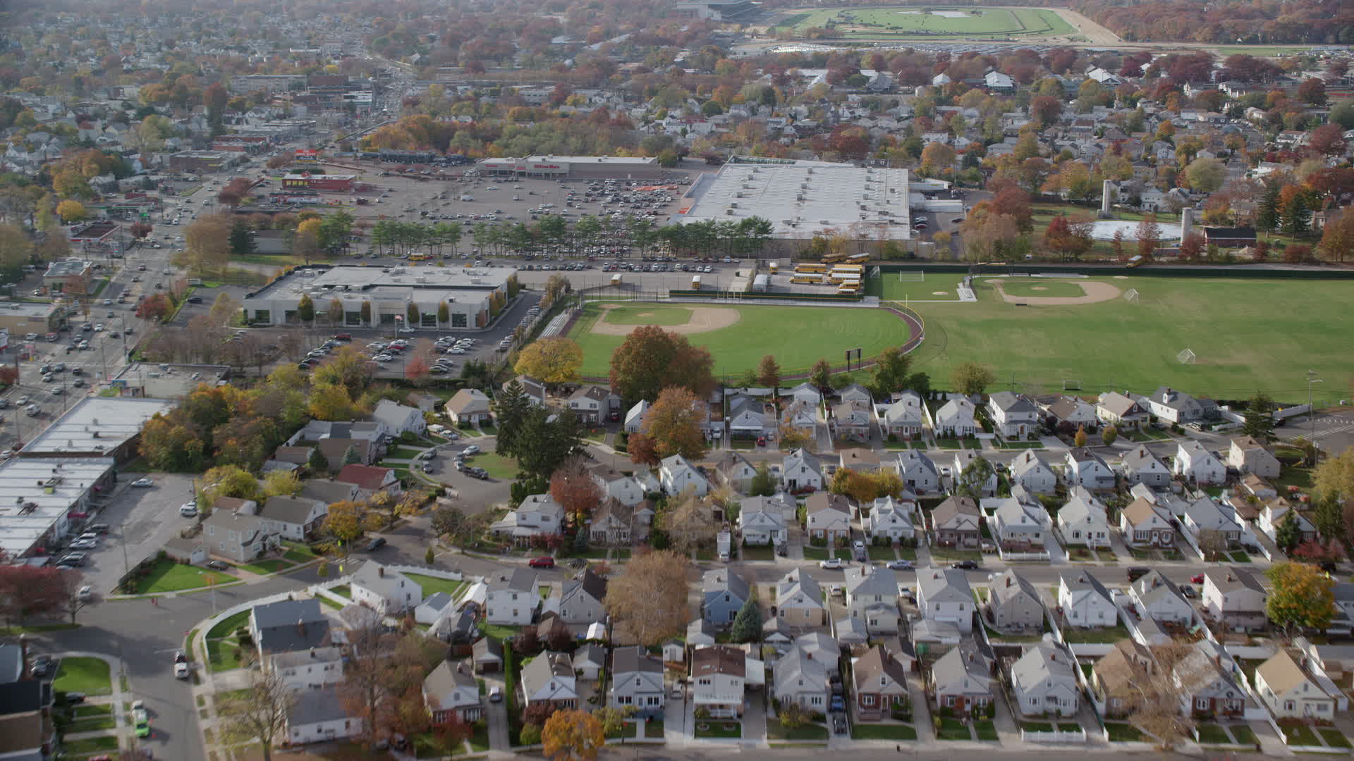 6K stock footage aerial video of homes, school baseball fields and store in Autumn, Elmont, New