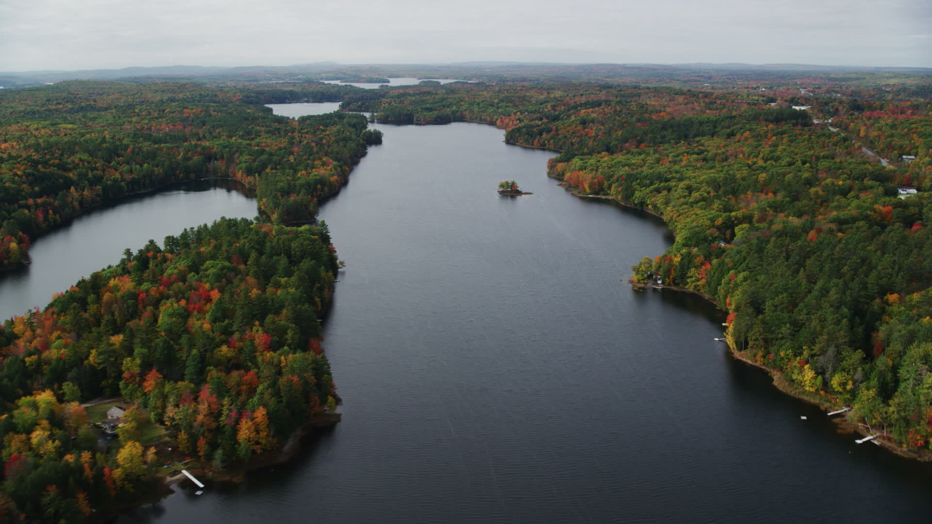 5.5K stock footage aerial video flying by Upper Narrows Pond, dense forest in autumn, Winthrop