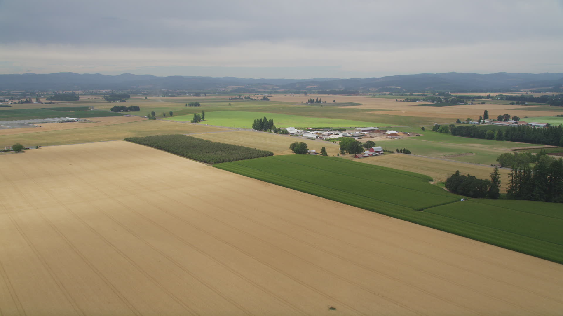 5K stock footage aerial video fly over crop fields to approach a farm
