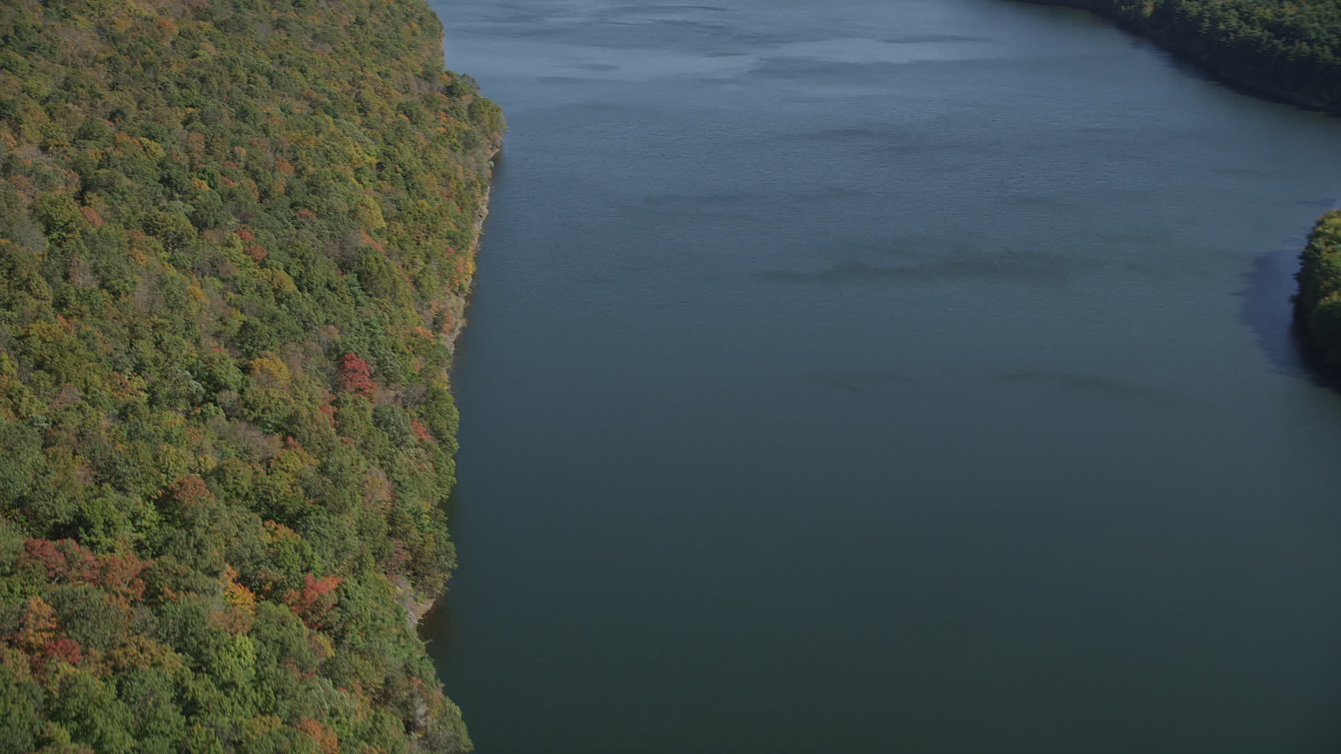 4K stock footage aerial video pan from lake to forest with fall foliage
