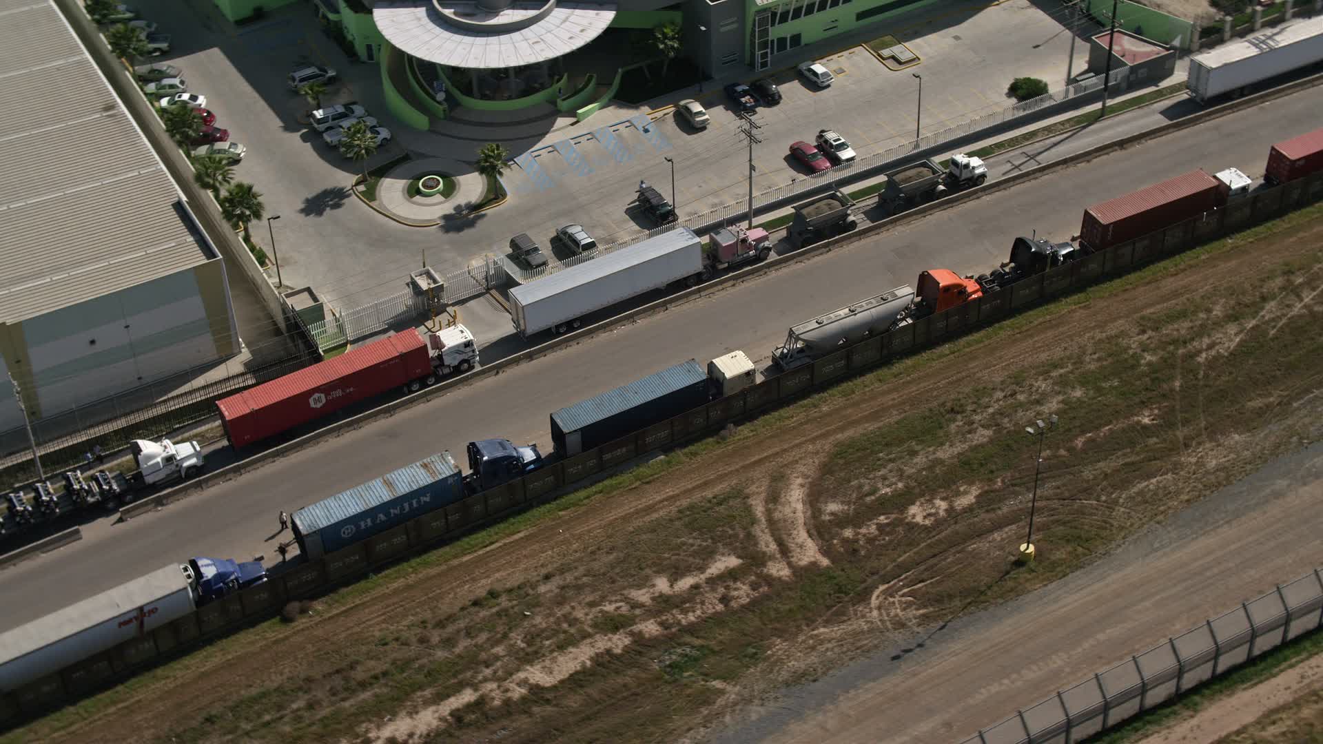 4K stock footage aerial video of a ling of big rigs by a warehouse, Tijuana, Mexico Aerial Stock