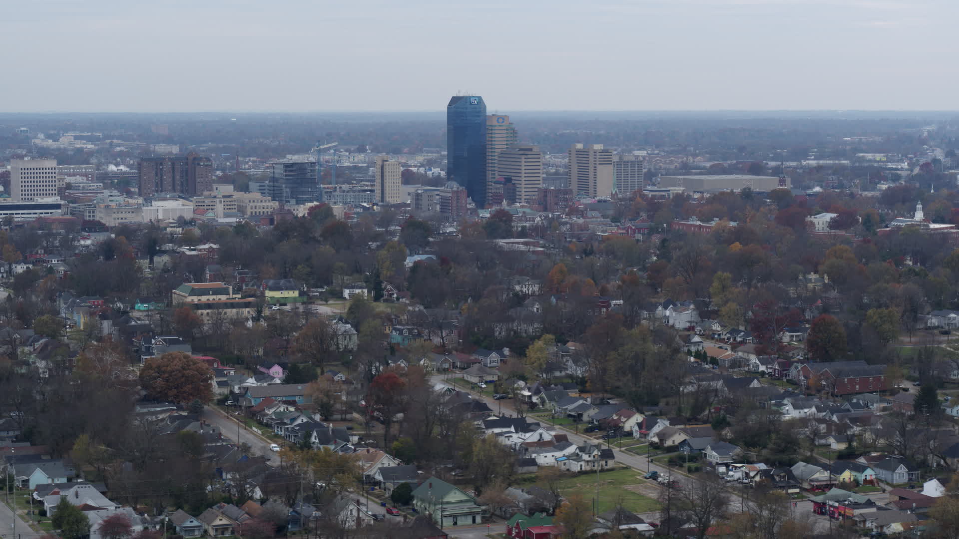5.7K stock footage aerial video of city skyline while flying past treelined neighborhoods
