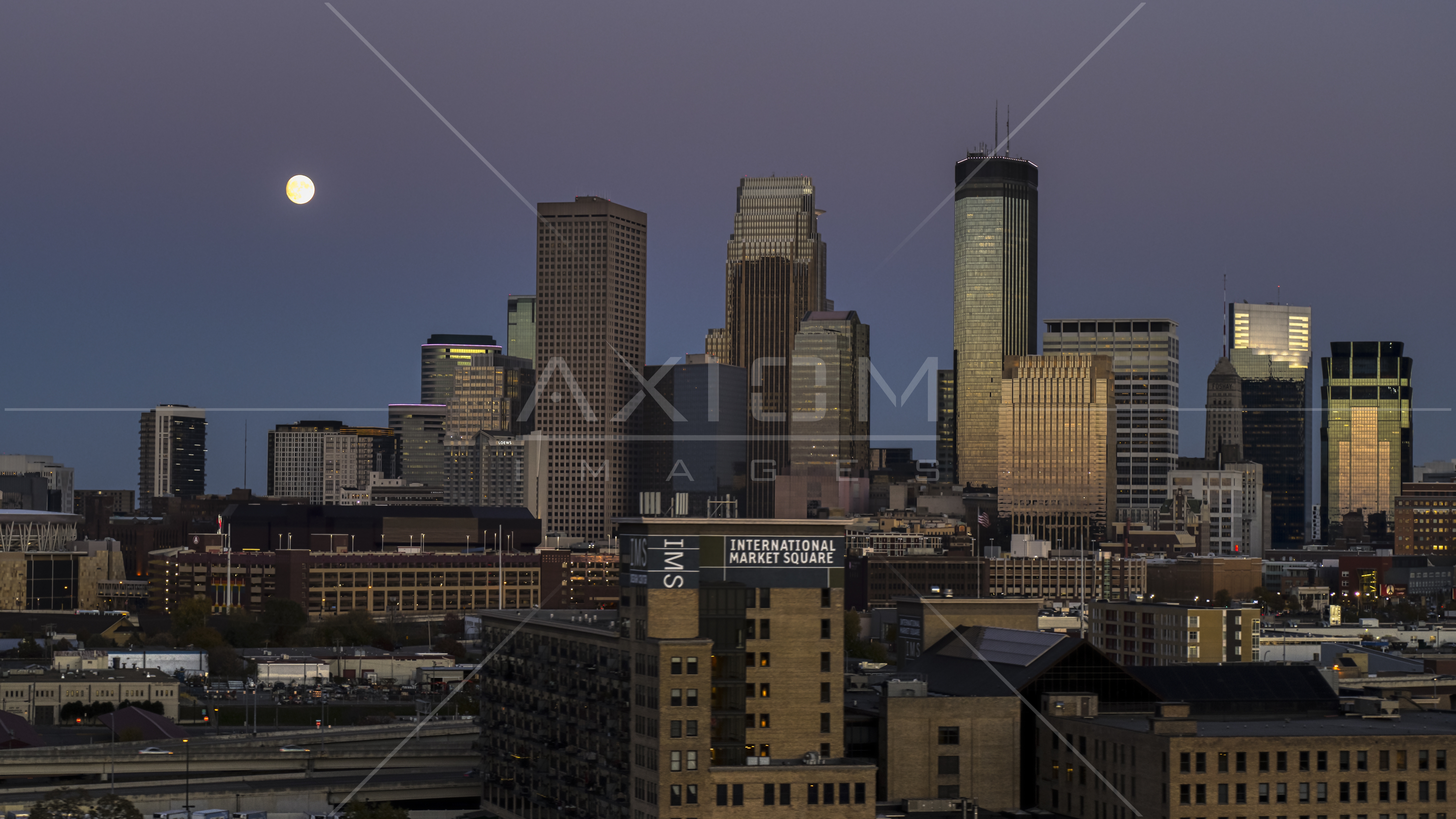The moon above tall skyscrapers of the city's skyline at twilight