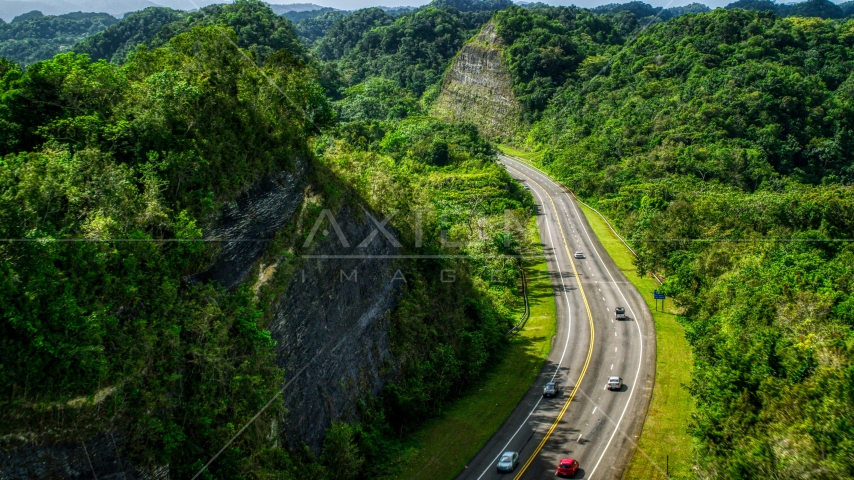 Light highway traffic through lush green mountains, Karst Forest, Puerto Rico Aerial Stock Photo AX101_078.0000299F | Axiom Images