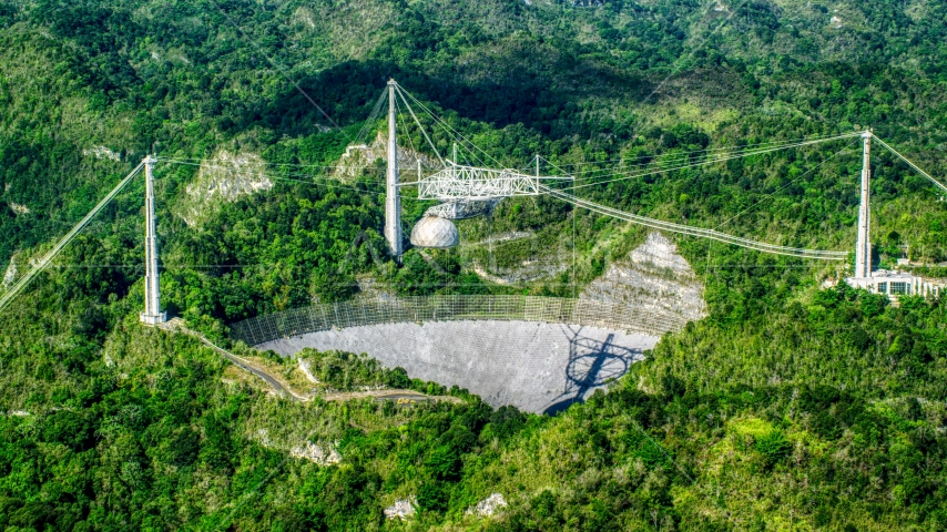Wide shot of the Arecibo Observatory among lush green forests, Puerto Rico Aerial Stock Photo AX101_090.0000276F | Axiom Images
