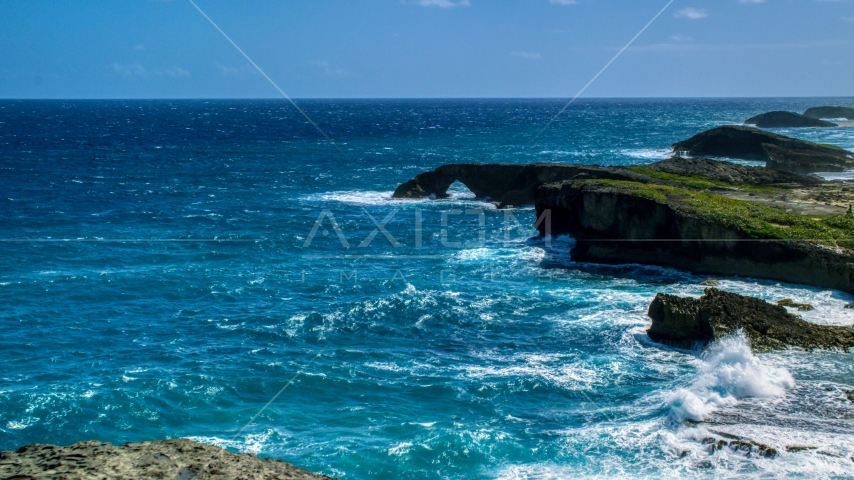 A rock arch in the blue water of a Caribbean island, Arecibo, Puerto Rico Aerial Stock Photo AX101_161.0000329F | Axiom Images