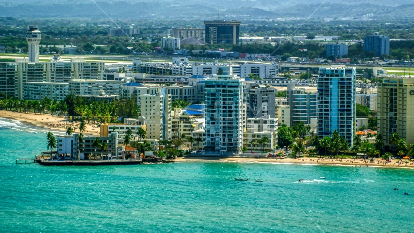 Apartment buildings on the coast by blue Caribbean waters, Carolina, Puerto Rico Aerial Stock Photo AX102_008.0000153F | Axiom Images